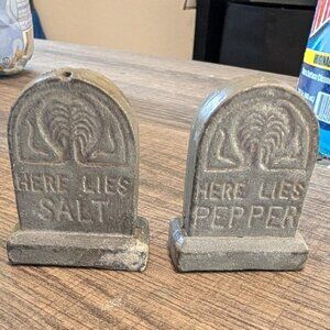 Cast metal tombstone-shaped salt and pepper shakers reading 'Here Lies Salt' and